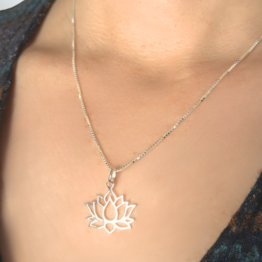 Silver lotus flower necklace on a person wearing a dark blue top.