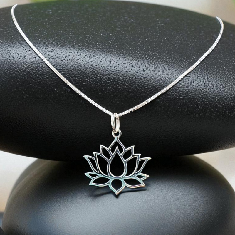 Load image into Gallery viewer, Silver lotus flower necklace on a black stone with greenery in the background
