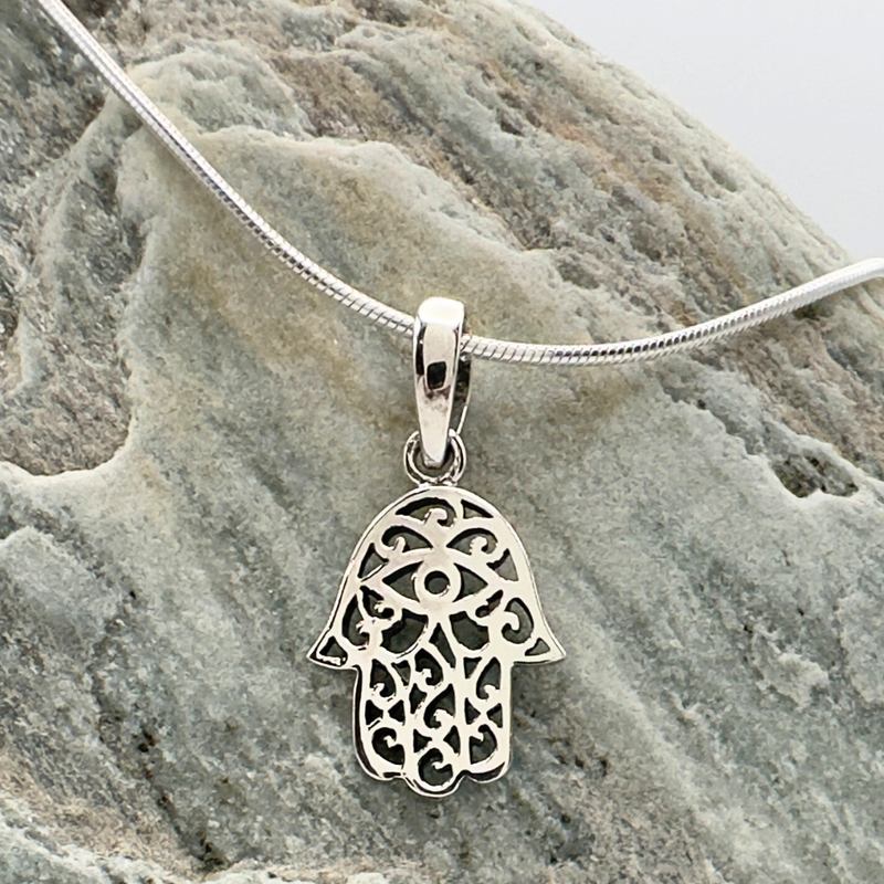 Load image into Gallery viewer, Silver Hamsa pendant on a chain against a stone background
