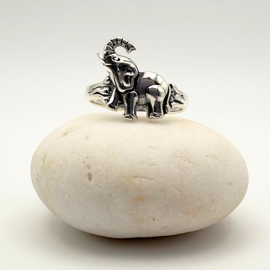 Silver elephant ring on a white stone with a white background