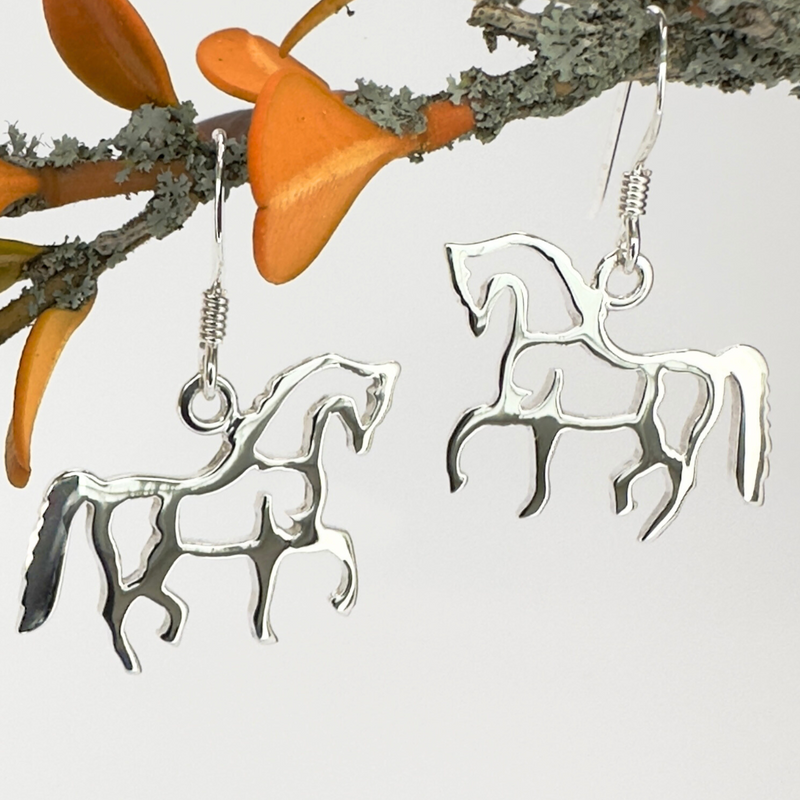 Load image into Gallery viewer, Silver horse-shaped earrings on a branch with orange flowers.
