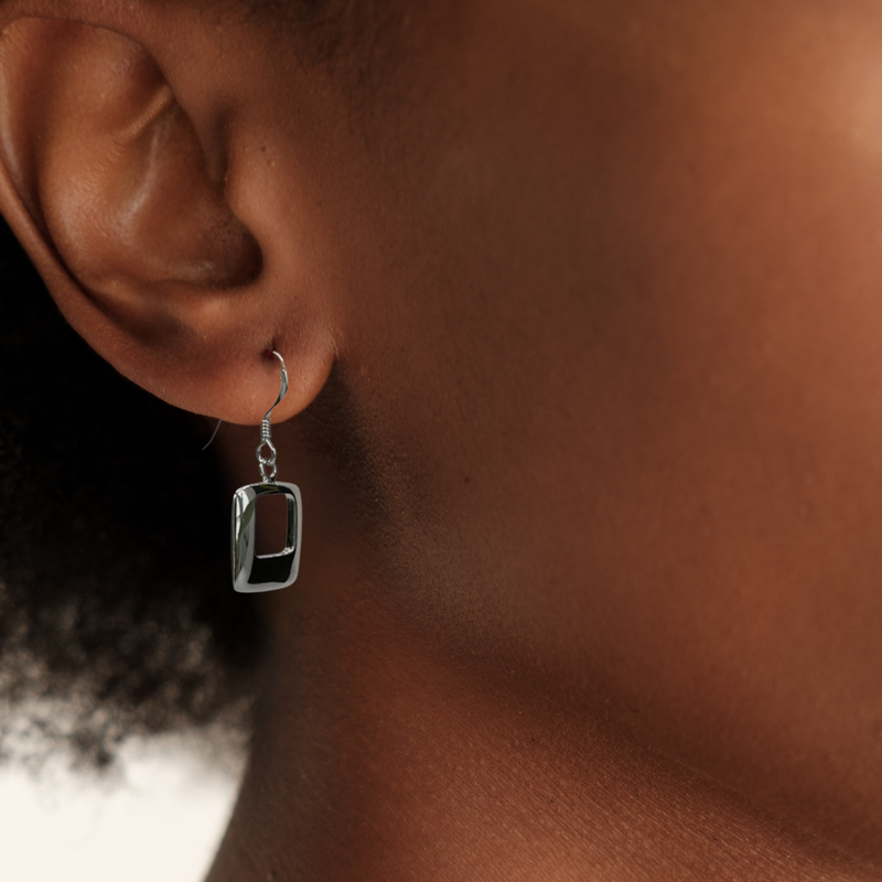 Load image into Gallery viewer, Close-up of an ear wearing a silver earring with a clear gemstone.
