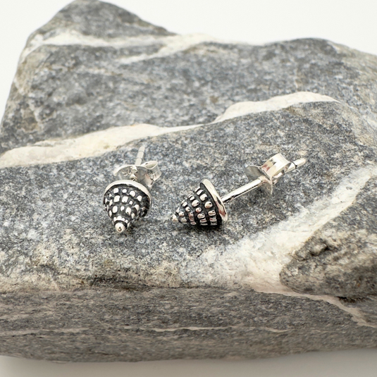 Silver stud earrings on a piece of gray stone