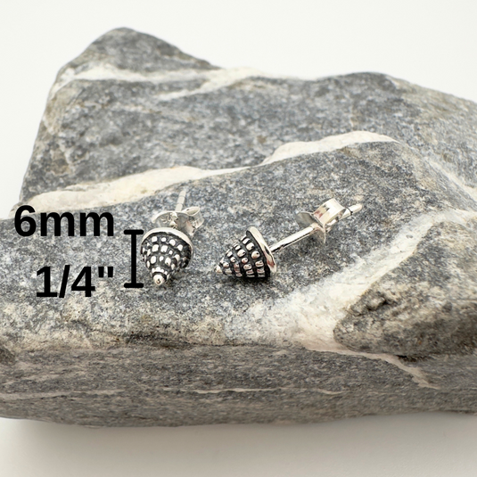 Pair of silver stud earrings on a rock with measurements displayed.