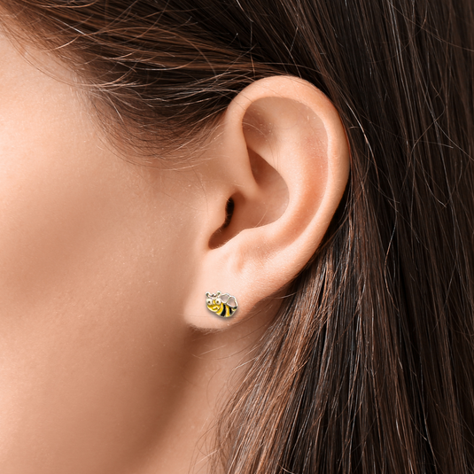Close-up of an ear wearing a bee-shaped earring with a blurred background