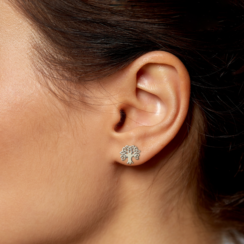 Load image into Gallery viewer, Close-up of an ear wearing a silver tree-shaped earring against a neutral background
