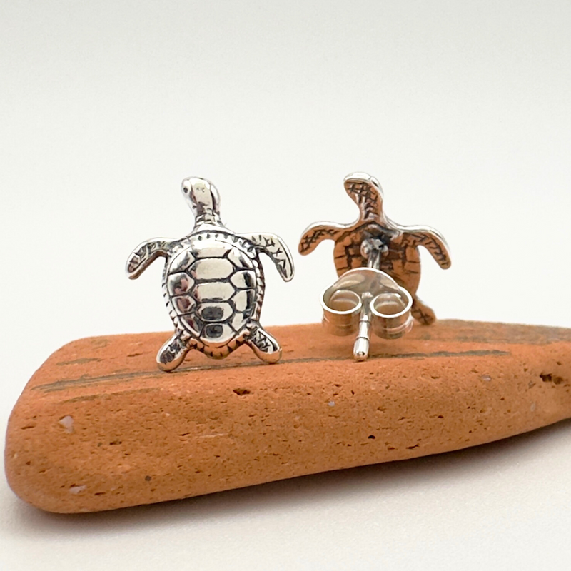Load image into Gallery viewer, Two turtle-shaped earrings on a piece of driftwood with a white background
