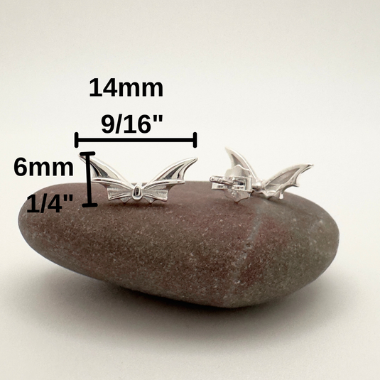 Silver earrings on a rock with measurements indicated