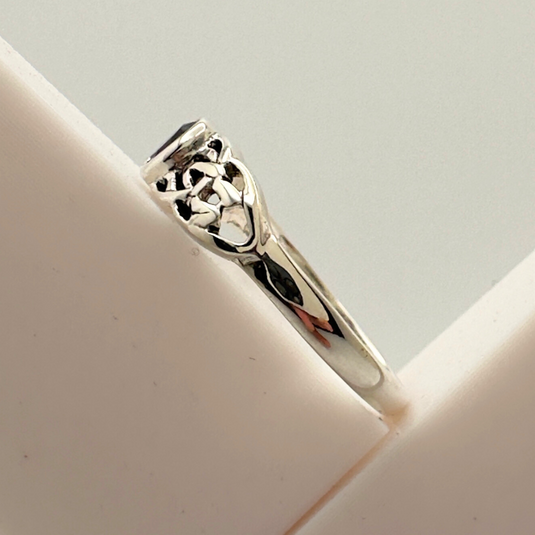 Silver ring with intricate design on a light gray background