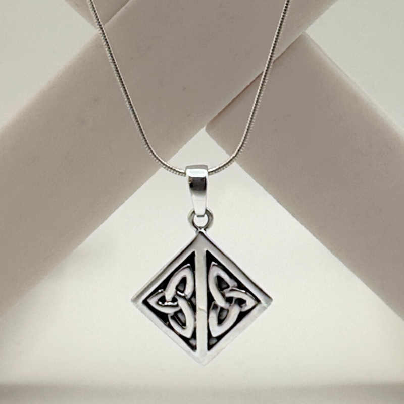 Load image into Gallery viewer, Silver pendant with Celtic design on a beige background
