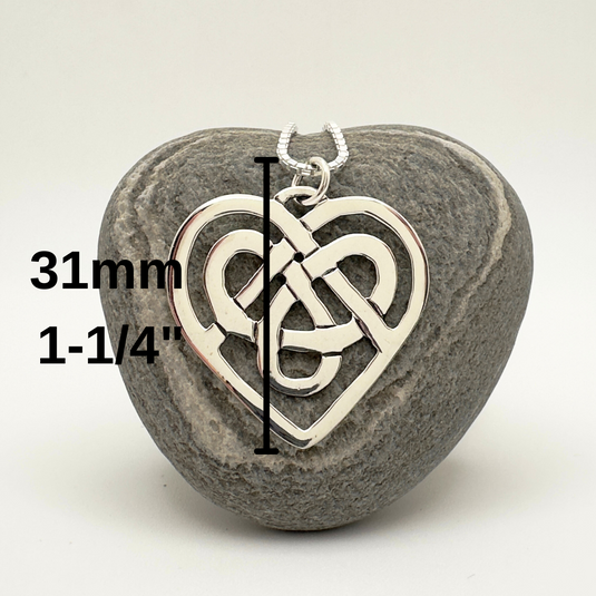 Heart-shaped pendant with Celtic knot design on a gray stone, measurement text overlay.