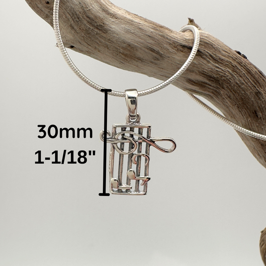 Silver pendant on a chain with measurement details, hanging on a wooden branch.