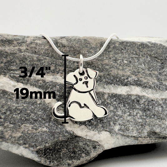 Silver dog pendant necklace on a rock with measurements displayed