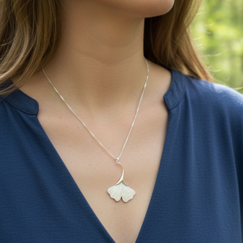 Load image into Gallery viewer, Silver necklace with a pendant worn by a person in a blue top against a blurred green background
