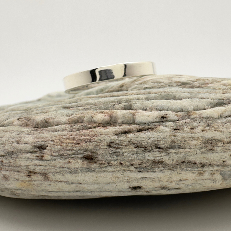 Load image into Gallery viewer, Silver ring on a textured stone surface with a white background
