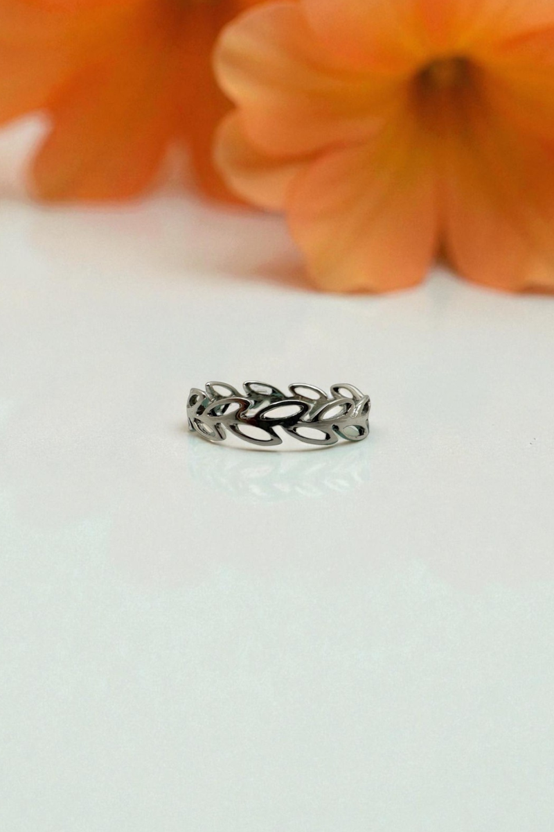 Load image into Gallery viewer, Silver ring with leaf design on a white surface with orange flowers in the background
