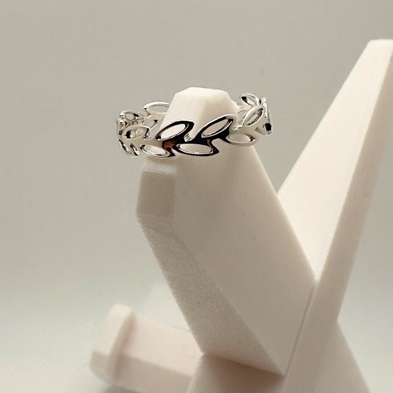 Load image into Gallery viewer, Silver ring with leaf design on a white stand against a light gray background
