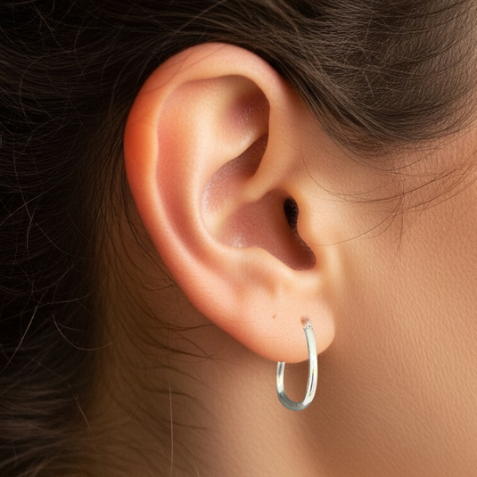 Close-up of an ear wearing a silver hoop earring with blurred background