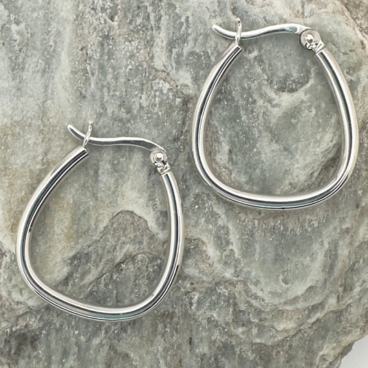 Silver hoop earrings on a textured stone surface