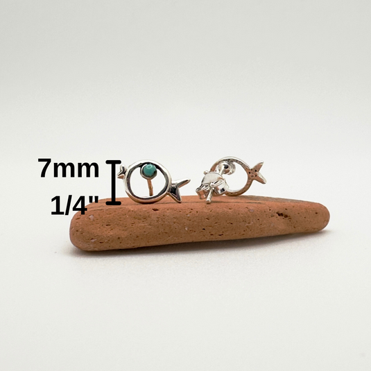 Two silver earrings on a piece of wood with measurement text