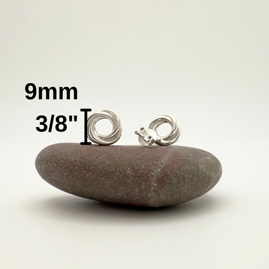 Silver earrings on a stone with measurement text on a white background