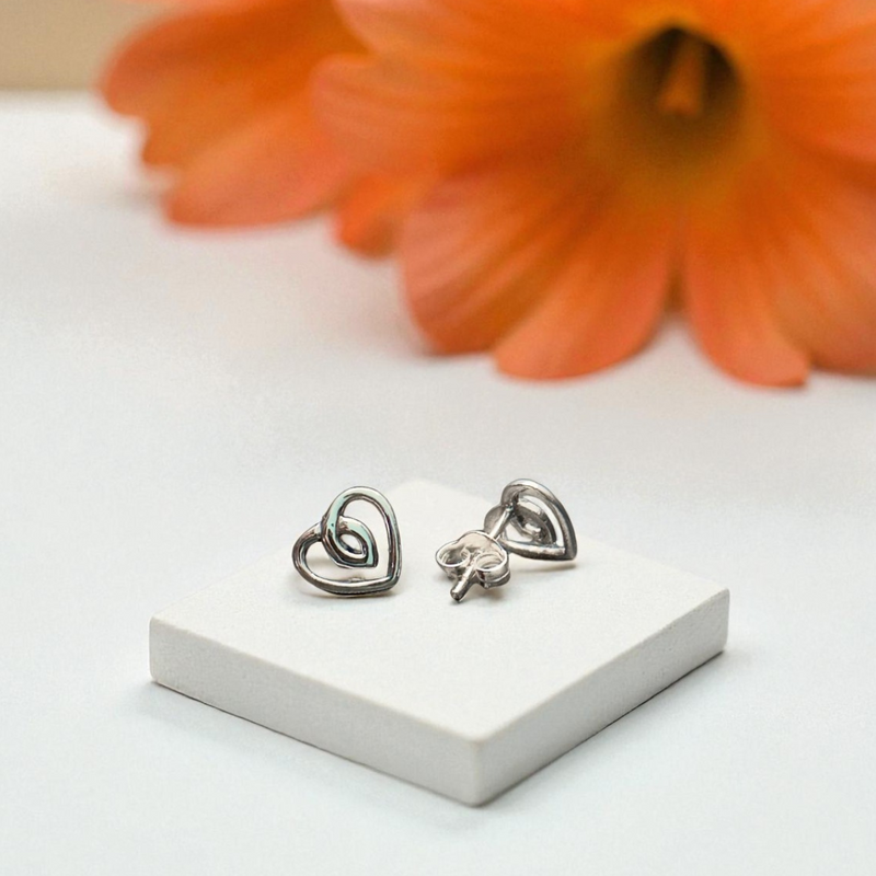 Load image into Gallery viewer, Heart-shaped earrings on a white stand with an orange flower in the background
