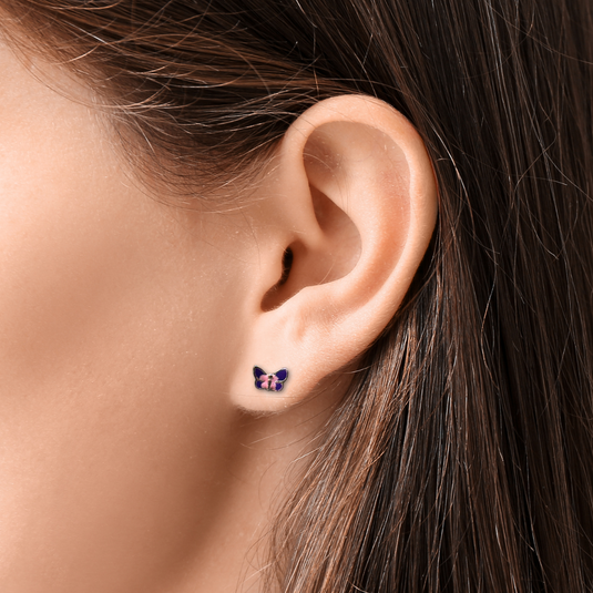 Close-up of an ear wearing a butterfly-shaped earring with dark hair and skin.