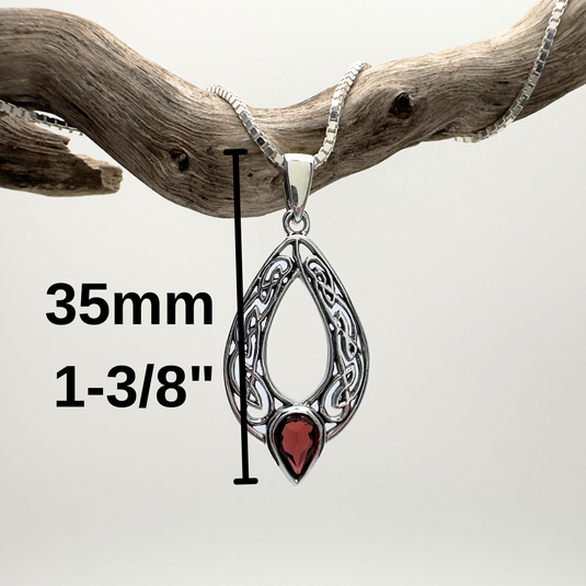 Silver pendant with red stone on a branch, measurement label included