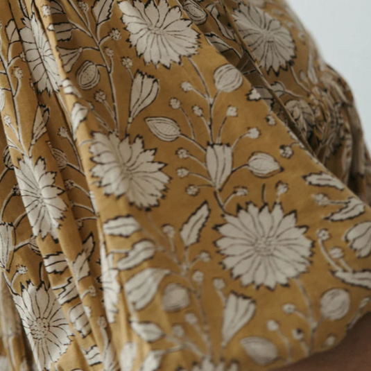 Close-up of a fabric with a floral pattern on a mustard yellow background